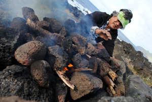 Native Rapa Nui preparing fire for cooking fish at Easter Island