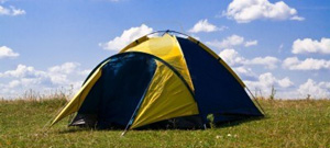 Camping tent with grass and blue sky with white clouds