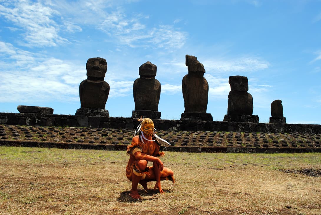 Body painted with kiea, the traditional earth pigment, in front of the moai of Tahai
