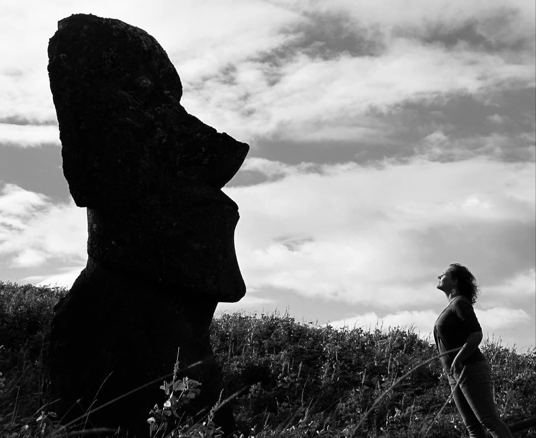 Woman looking up at a single moai statue in profile at Rano Raraku