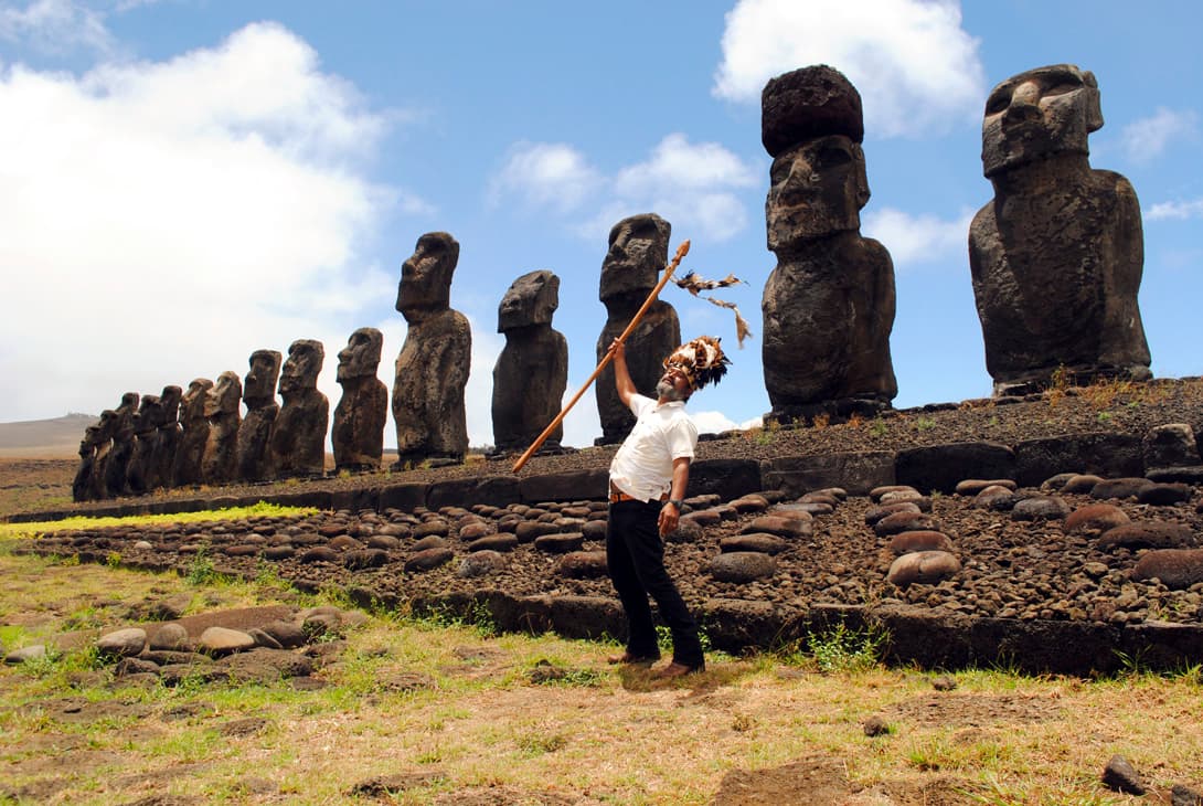 Rapa Nui native in traditional feather headdress in front of Ahu Tongariki at Easter Island