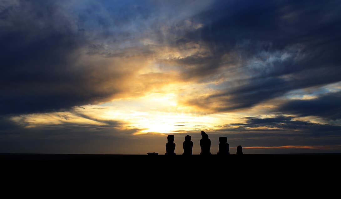 Silhouettes of moai statues of Ahu Vai 'Uri at sunset at Tahai, Easter Island (Rapa Nui)