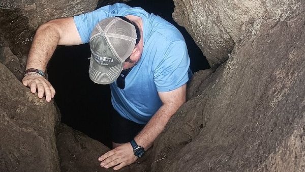 Demonstrating the narrow entrance to an Ana Kionga, a defensive refuge used in ancient tribal times.