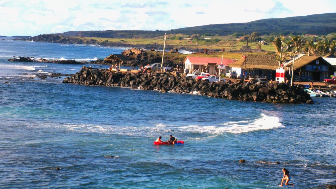 Surfers and swimmers enjoying the ocean at Pea Beach in Hanga Roa.