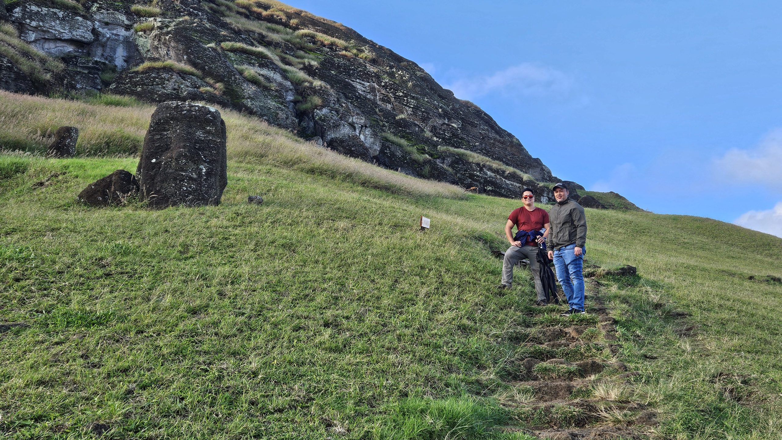 Visitor walking through the trails of Rano Raraku, observing moai in different stages of carving alongside a private guide.
