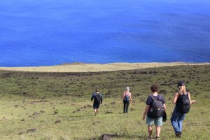 Travelers walking along Rapa Nui's northern coastline to experience a true digital escape surrounded by nature and the Pacific Ocean.