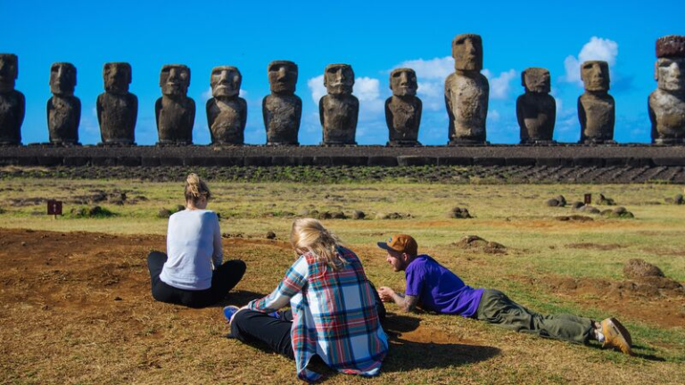 Travelers relaxing in front of Ahu Tongariki after disconnecting in Rapa Nui.