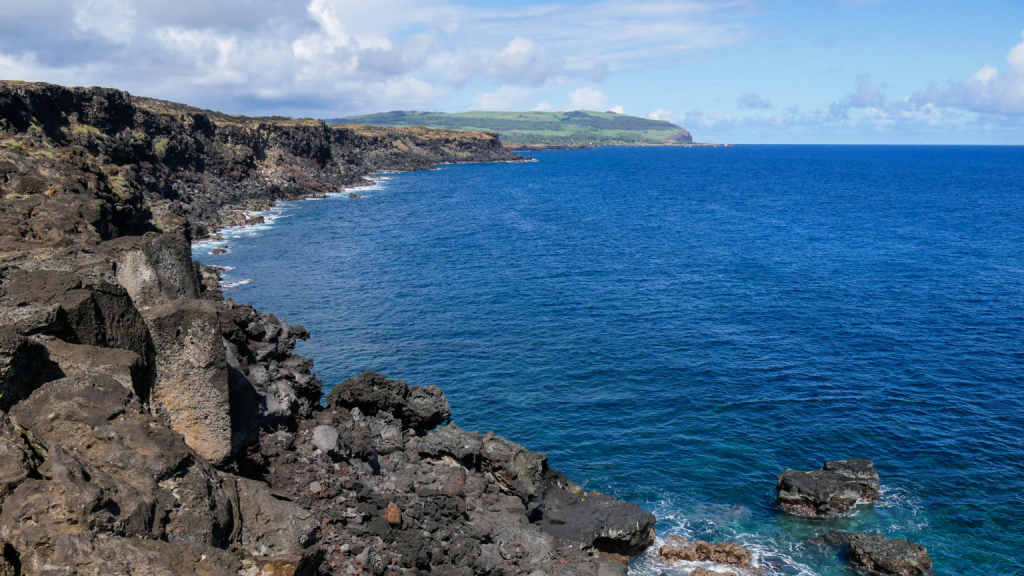 The Pacific Ocean crashing against the volcanic cliffs surrounding Ana Kakenga, a landscape shaped by thousands of years of geological activity and coastal erosion.