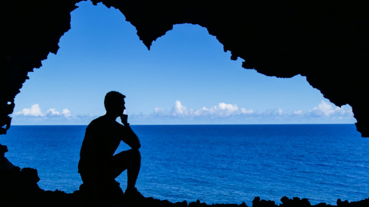 A visitor's silhouette highlights the impressive scale of Ana Kakenga, also known as the Cave of the Two Windows.