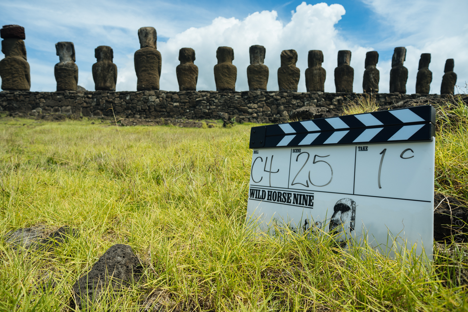 Film clapperboard for the movie Wild Horse Nine Rapa Nui with stone moai statues in the background during filming.