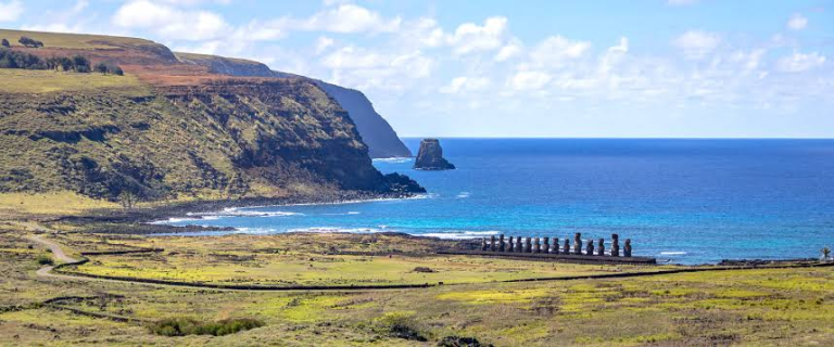 Panoramic view of Ahu Tongariki with the blue sea, the volcanic rim, and Motu Maratiri in the background in Rapa Nui.