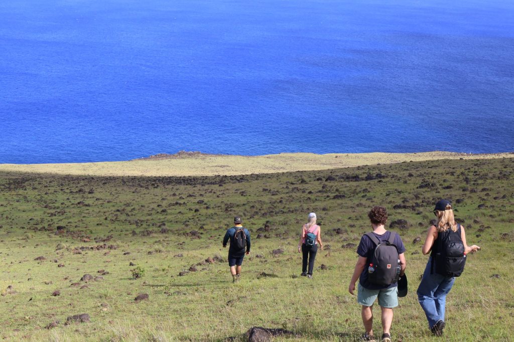 Turistas caminando por la costa norte para desconectarte en Rapa Nui rodeados de naturaleza y el océano Pacífico.