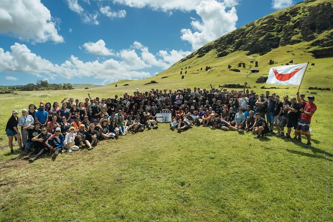 Equipo de producción y elenco de la película Wild Horse Nine Rapa Nui posando juntos con la bandera de Rapa Nui y la cantera de Rano Raraku de fondo.