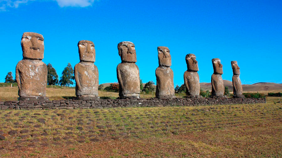 The seven moai of Ahu Akivi standing beneath a clear blue sky during an archaeological route in Rapa Nui.