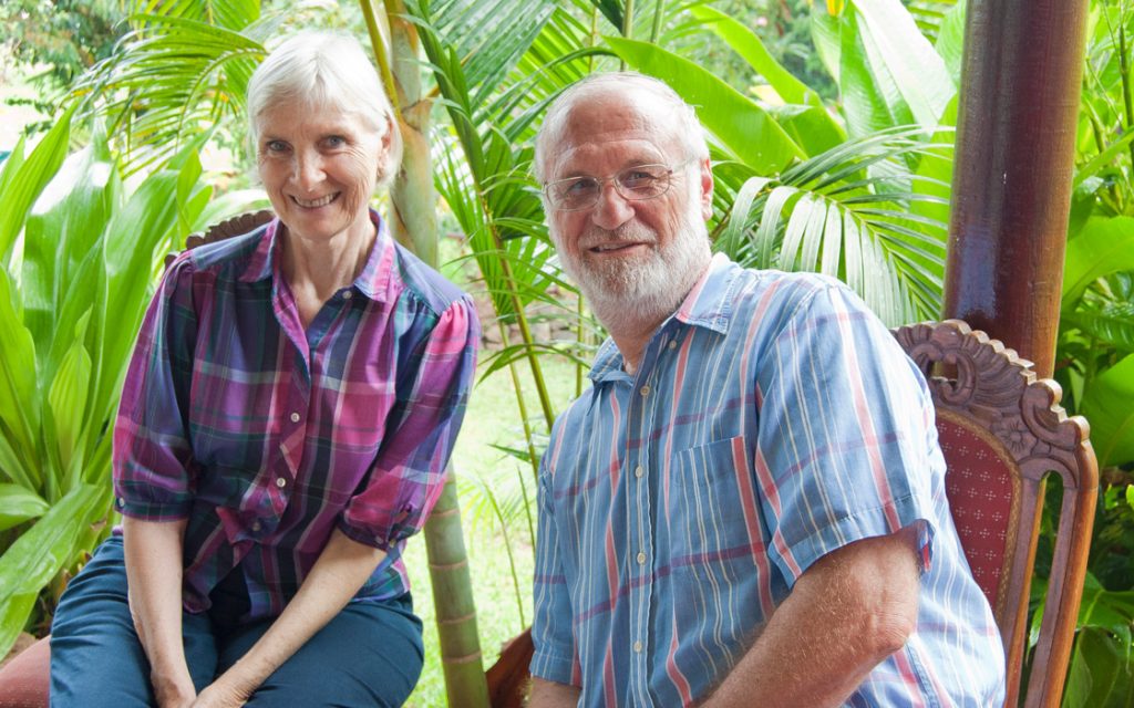 Nancy Weber y su esposo Roberto Weber sonriendo al aire libre en un jardín, reconocidos por su labor lingüística en Rapa Nui.