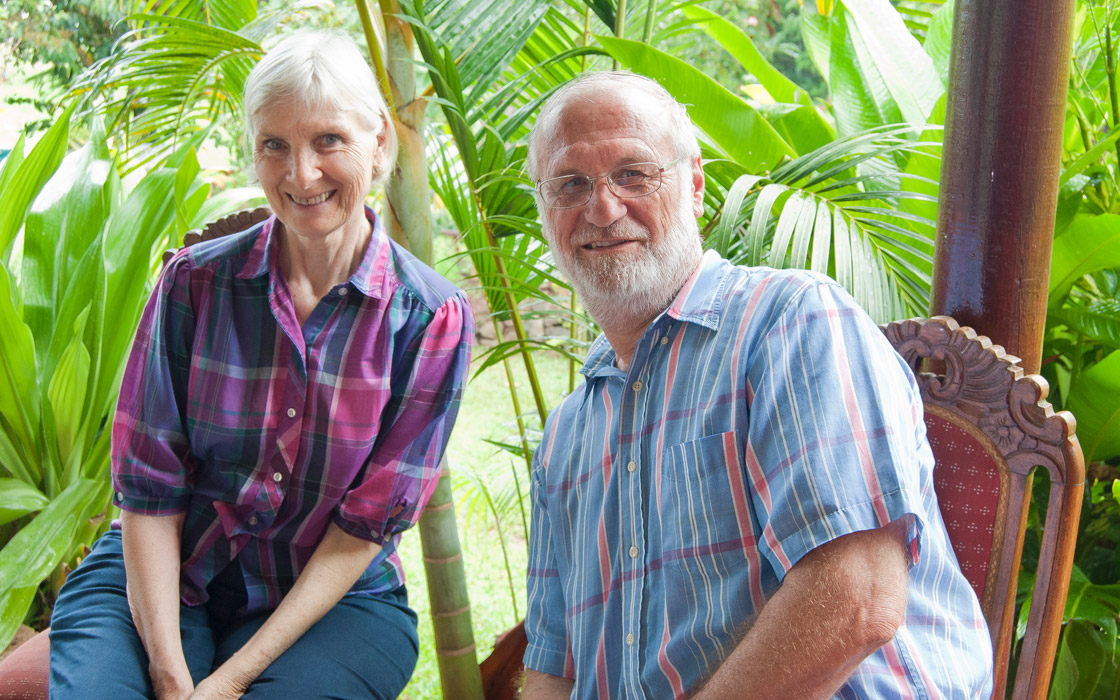 Nancy Weber y su esposo Roberto Weber sonriendo al aire libre en un jardín, reconocidos por su labor lingüística en Rapa Nui.