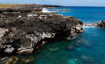 Rocky coastline by green and blue ocean at Rapa Nui (Easter Island)